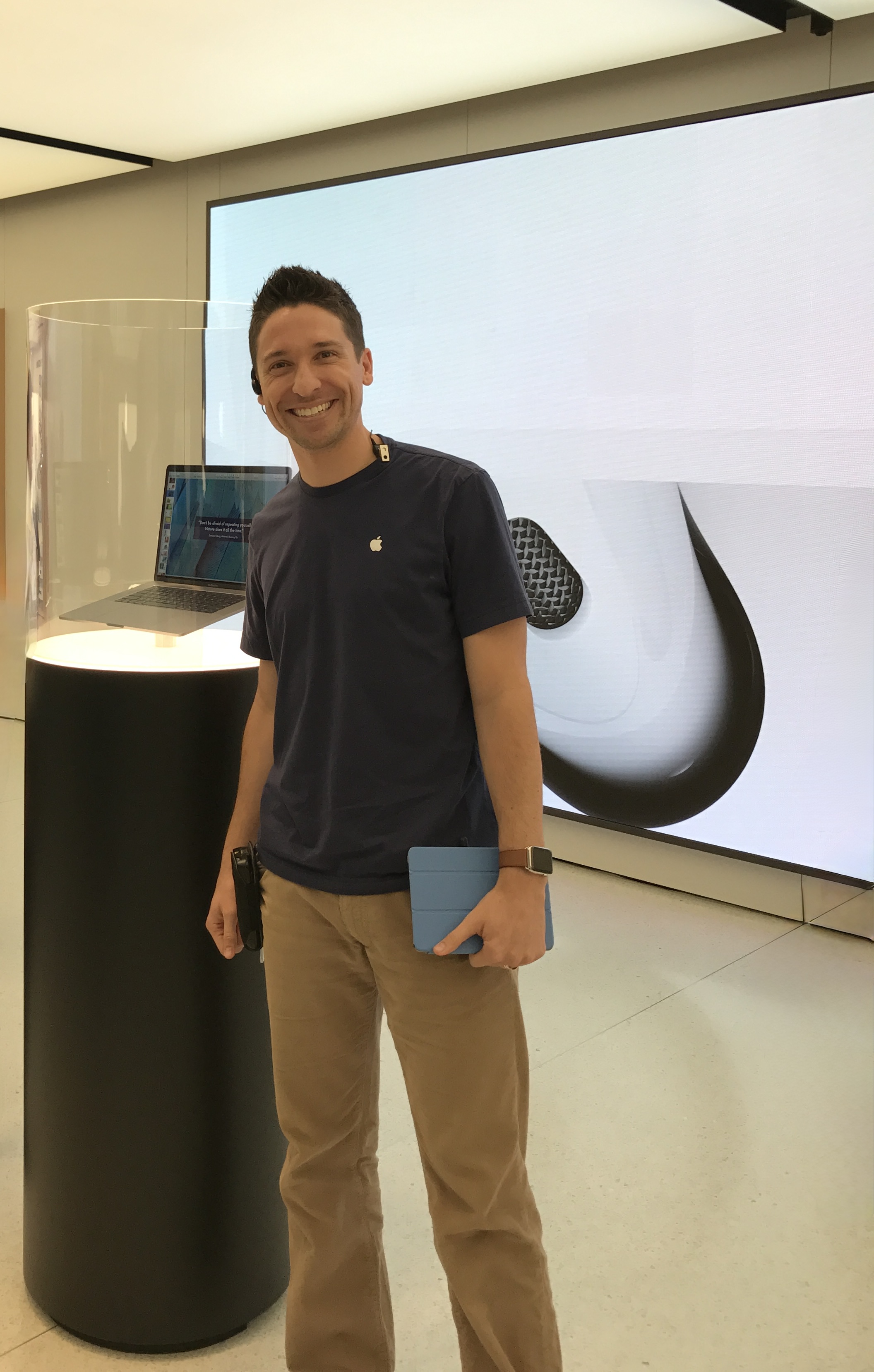 Ross Loofbourrow standing inside an Apple Store in a navy Apple shirt, smiling