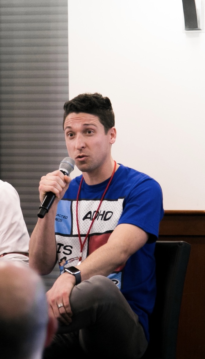 Ross on an ADHD panel discussion, holding a microphone and wearing an ADHD t-shirt