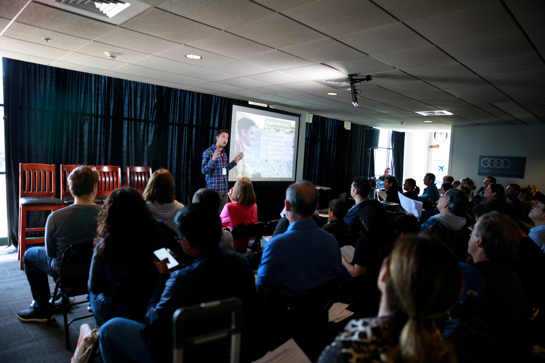 Ross presenting at Ed Rev with full audience visible and Audi logo on the wall