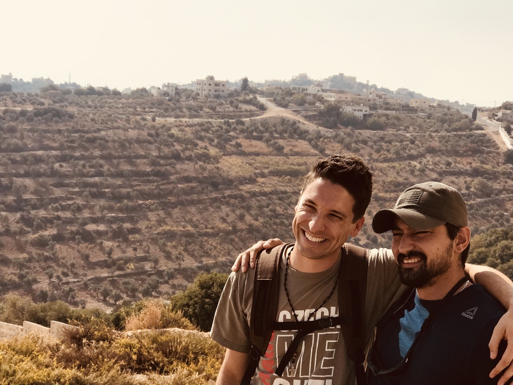 Ross and Youseff smiling together on a Jordanian hillside, arms around each other